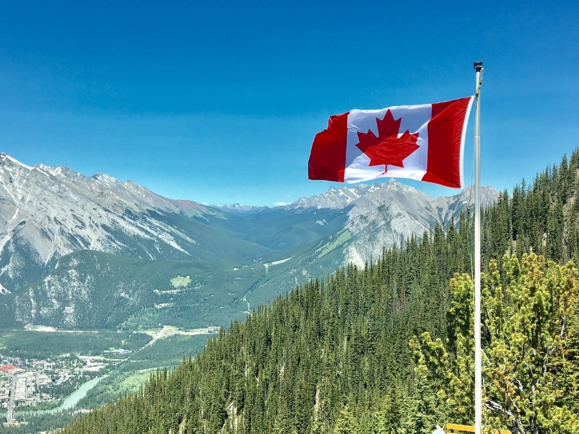 The Canadian flag flying above a mountain valley in the Rockies
